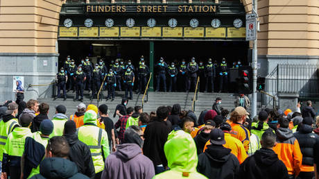 Protestors walk past police outside Flinders Street station in Melbourne, Australia. September 21, 2021. © Getty Images / Asanka Ratnayake