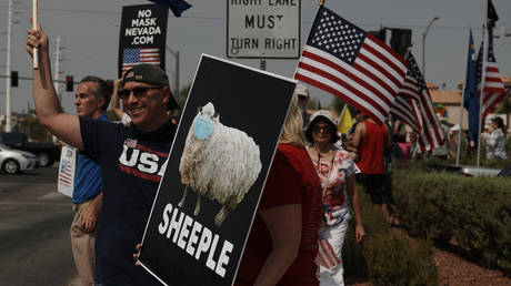 Protestor Colene Stevens holds a sign with a sheep wearing a mask in Las Vegas, Nevada. © Bridget BENNETT / AFP