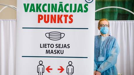 A medical worker waits for patients next to a sign for social distancing measures at a local community sports hall converted into a vaccination centre in Ventspils, Latvia. © Gints Ivuskans / AFP