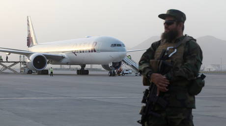 A member of Taliban security forces stands guard in front of a Qatar Airways airplane boarding passengers at the international airport in Kabul, Afghanistan, September 10, 2021.