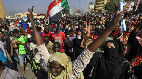 Sudanese protesters lift national flags as they rally on 60th Street in the capital Khartoum, to denounce overnight detentions by the army of government members, on October 25, 2021. © AFP