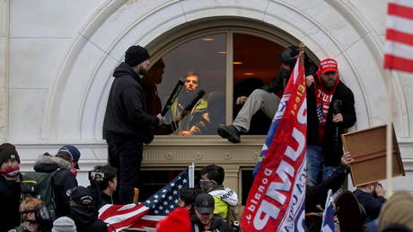 Supporters of then-U.S. President Donald Trump climb through a window they broke as they storm the U.S. Capitol Building, January 6, 2021