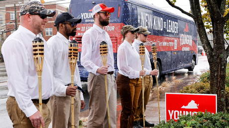 A group dressed as white supremacists poses in front of Republican gubernatorial candidate Glenn Youngkin's campaign bus in Charlottesville, Virginia, October 29, 2021.