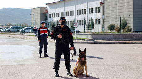 Turkish gendarme Bulent Okurcan stands guard with his 7-year-old malinois police dog Ihbar outside the courthouse of Sincan, outside Ankara, on April 7, 2021, before the verdict hearing in the trial of 497 defendants over the 2016 failed coup attempt. © AFP / Adem Altan