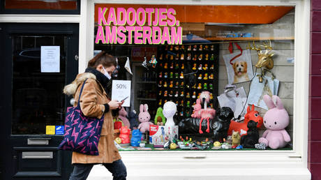 FILE PHOTO. A woman wearing a protective mask walks past a store in Amsterdam, Netherlands.
