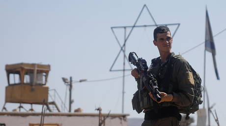 An Israeli soldier stands guard as demonstrators take part in a protest in support of Palestinian farmers and against Israeli settlements, in Beita, in the Israeli-occupied West Bank October 10, 2021. © REUTERS / Raneen Sawafta