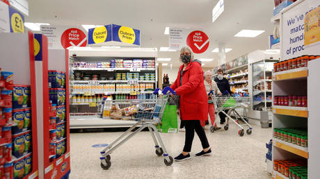 A woman wearing a face mask pushes a shopping cart at a Tesco supermarket in Hatfield, Britain, October 6, 2020.