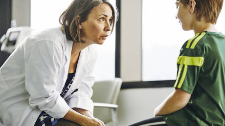 Doctor talking to child in exam room © Getty Images / The Good Brigade