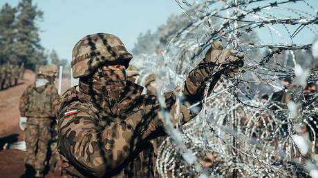 A Polish soldier instals barbed wire on the Poland/Belarus border near Kuznica, Poland, in this photograph released by the Polish Defence Ministry, November 9, 2021. © Reuters / Irek Dorozanski
