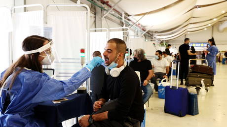 FILE PHOTO: A healthcare worker takes a swab sample from a traveler at the Ben Gurion International Airport in Israel, October 13, 2021.