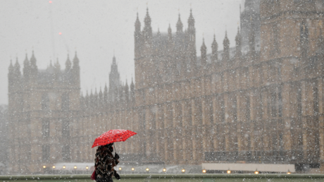 A person crosses the Westminster Bridge, with the Palace of Westminster on the background, as snow falls in London, Britain. © REUTERS / Toby Melville