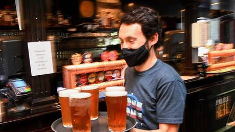 A customer carries a tray of beer to his table at a downtown pub in Melbourne. October 22, 2021. © AFP / William West