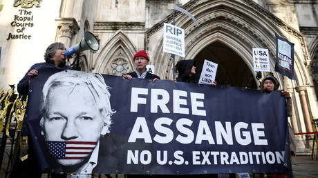Supporters of Julian Assange hold aloft placards and unfurl a banner outside the Royal Courts of Justice in London, UK, December 10, 2021. © Reuters/Henry Nicholls