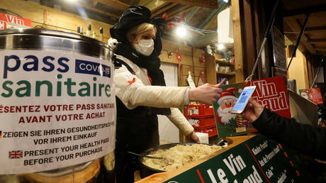 فروشنده کارت سلامت اجباری مشتری را در بازار کریسمس در کولمار، فرانسه، 14 دسامبر 2021 اسکن می کند. © رویترز / ایو هرمان