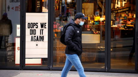 A man wearing a face mask walks past a closed store in London, Britain, November 5, 2020 © Reuters / John Sibley