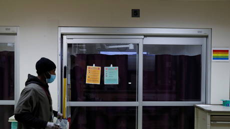 A housekeeper passes the isolation room of a Covid-19-positive patient in Chicago, Illinois, US, December 2, 2020. © REUTERS/Shannon Stapleton