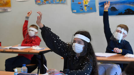 Schoolchildren wearing protective mouth masks and face shields attend a course in a classroom at Claude Debussy college in Angers, western France, on May 18, 2020. © Damien MEYER / AFP