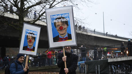 Protesters hold banners of German Health Minister Karl Lauterbach at a rally against Covid-19 restrictions. December 18, 2021. © AFP / Ina Fassbender