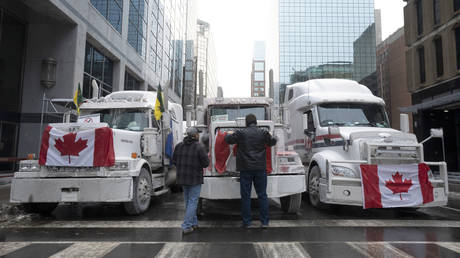 Truck drivers hang a Canadian flag on the front grill of a truck parked in downtown Ottawa as a convoy of truckers protests vaccine mandates, in Ontario, Canada, February 2, 2022.