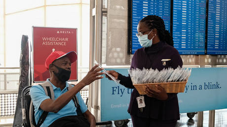 A Delta Airline employee gives face mask to passenger during check in at the Ronald Reagan National Airport in Arlington, Virginia