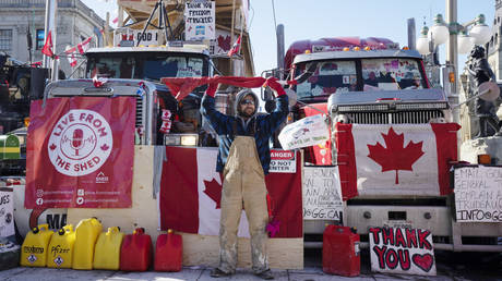 A protester holds a hockey stick wrapped in a Canadian flag above his head in Ottawa, Feb. 14, 2022