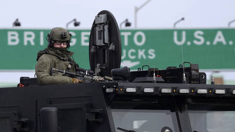 An Ontario Provincial Police tactical officer looks on from the top hatch of an armored vehicle near the Ambassador Bridge blocked by protesters against Covid-19 restrictions, in Windsor, Feb. 12, 2022