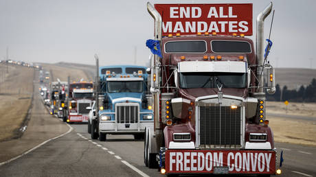 Anti-vaccine mandate demonstrators leave in a truck convoy after blocking the highway at the US border crossing in Coutts, Alberta, February 15, 2022.