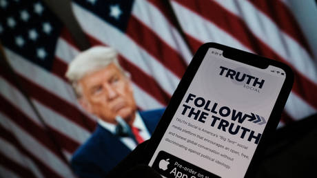 A person checks the App Store for ‘Truth Social’, with a photo of former US President Donald Trump in the background, in Los Angeles, October 20, 2021
