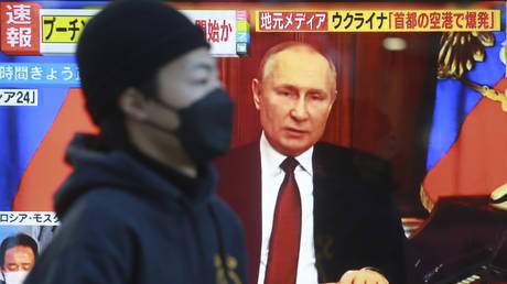 FILE PHOTO: A man walks past a TV screen with image of Russia's President Vladimir Putin in Tokyo, Feb. 24, 2022