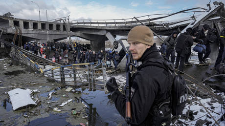 Des personnes marchent sous un pont détruit en fuyant Irpin, à la périphérie de Kiev, en Ukraine, le 8 mars 2022.