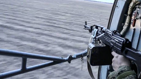 FILE PHOTO: A Russian soldier mans a gun turret on a military helicopter as it flies over an undisclosed location in Ukraine.