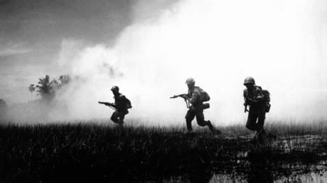 View of crack troops of the Vietnamese Army running across marshy terrain in Vietnam's delta country, during operations against the Communist Viet Cong guerillas, 1961. © Interim Archives / Getty Images