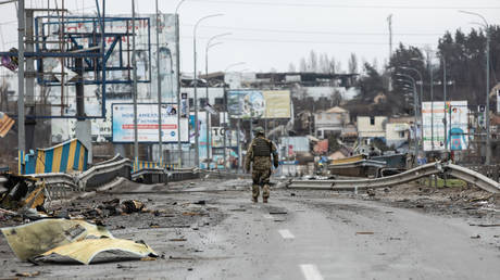 A Ukrainian soldiers walks past dead bodies on a destroyed road in Bucha, Kyiv region. ©Mykhaylo Palinchak / SOPA Images / LightRocket via Getty Images