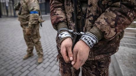 FILE PHOTO: A Ukrainian serviceman guards a handcuffed POW. © AFP / Fadel Senna