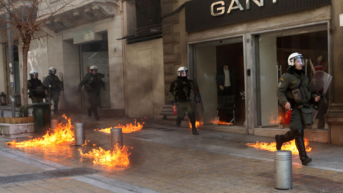 Riot police run by closed shops after protesters threw a petrol bomb following an anti-austerity march during a 24-hour strike in Athens February 20, 2013.(Reuters / Giorgos Moutafis)