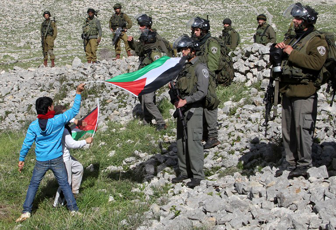 Children wave Palestinian flags in front of Israeli security forces as Palestinians set up a new camp to protest against Jewish settlements near the West Bank village of Burin on February 2, 2013. (AFP Photo / Jaafar Ashtiyeh)