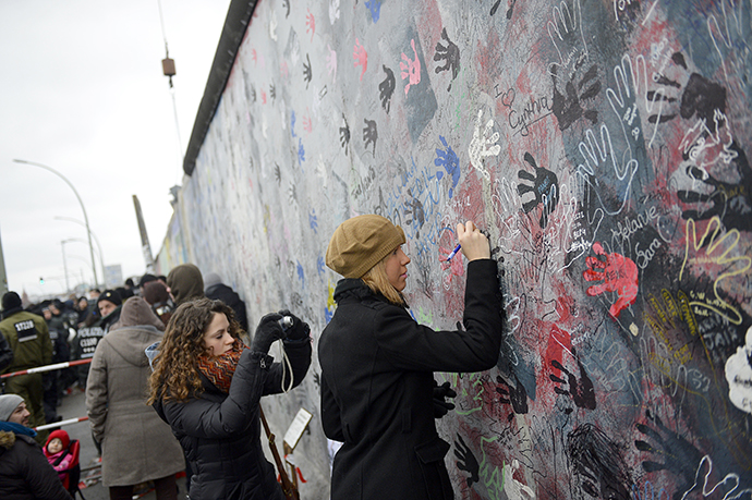 A woman writes on a part of the East Side Gallery. (AFP Photo / Odd Andersen)