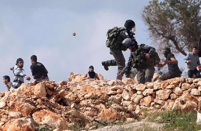 Palestinian protesters throws stones at Israel border policemen during a protest marking the 8th anniversary of their campaign against the controversial Israeli barrier in the West Bank village of Bilin near Ramallah March 1, 2013 (Reuters / Mohamad Torokman)