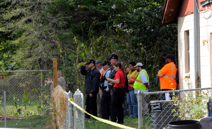 Rescue and engineering crews watch from a neighbouring backyard as other crew members work to evaluate the safety of a home where a sinkhole opened up and swallowed a man in Seffner, Florida, March 1, 2013 (Reuters / Brian Blanco)