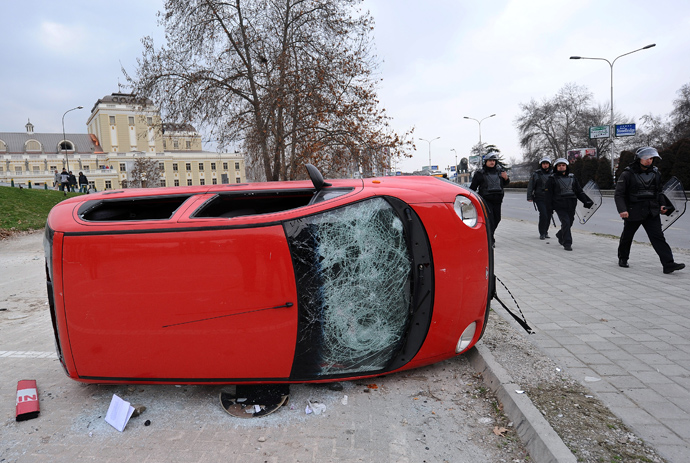 Macedonian riot police walk past a damaged car during clashes with ethnic Albanians in Skopje on March 2, 2013 (AFP Photo / Robert Atanasovski)
