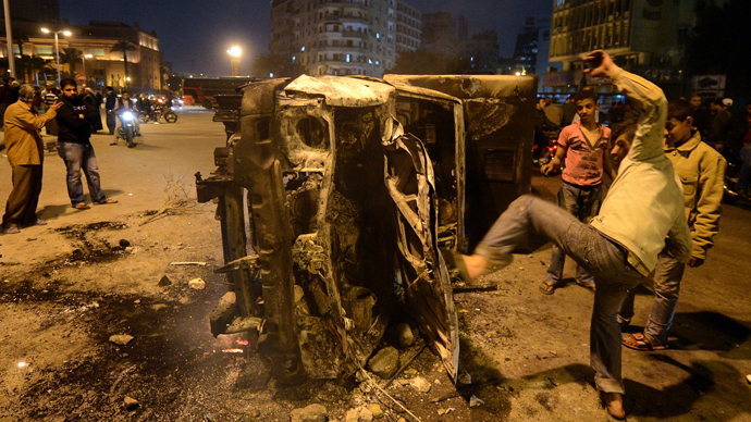 An Egyptian man gives a kick towards a police vehicle that has been burnt by angry protesters following clashes with plainclothes policemen in Cairoâs on Tahrir square on March 3, 2013 (AFP Photo / Khaled Desouki)