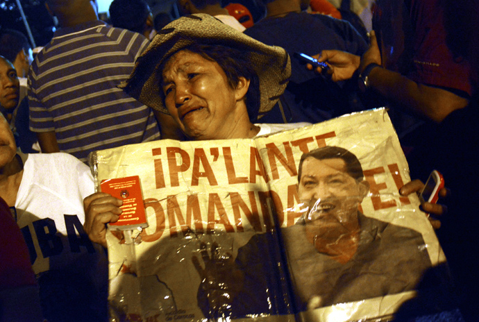 A supporter of Venezuelan President Hugo Chavez shows a sign with his portrait outside the Military Hospital in Caracas next to Army members on March 5, 2013, after knowing of his death (AFP Photo / Leo Ramirez)