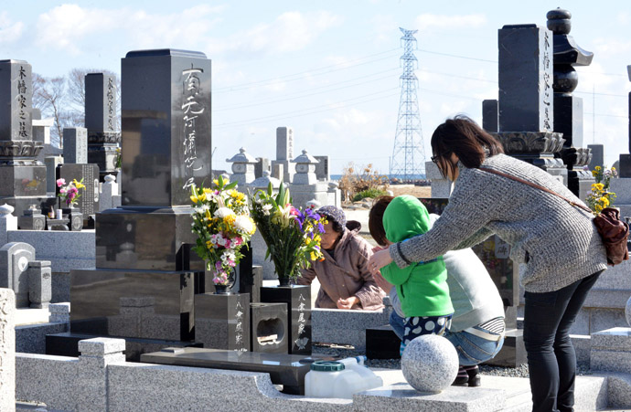 A family prays for their relatives killed by the 2011 tsunami at a cemetery in Minamisoma in Fukushima prefecture on March 11, 2013. (AFP Photo/Yoshikazu Tsuno)