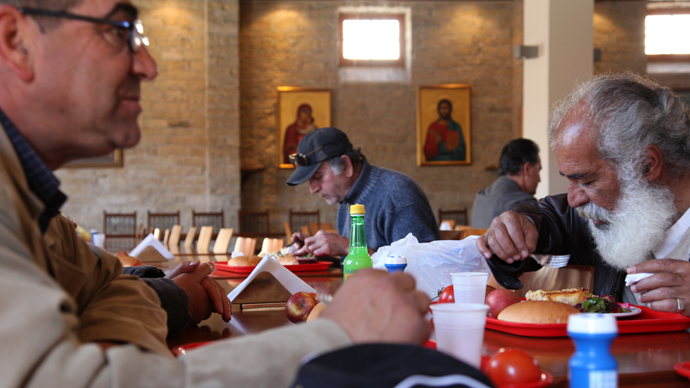 People in need eat meals provided as part of the food aid program launched by Limassol's bishop Athanasios at the Bishopric Church of Panagia Katholiki on February 12, 2013 in Limassol, Cyprus (AFP Photo / Barbara Laborde)
