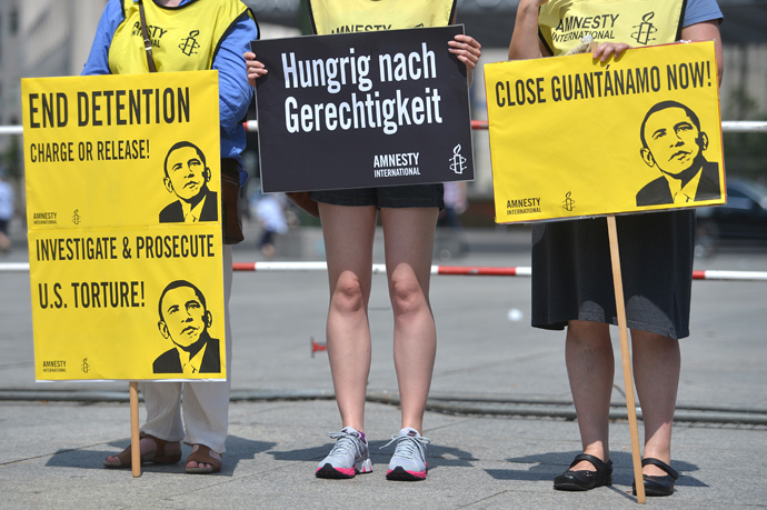 Activists from Amnesty International human rights association hold posters reading "End Detention Charge or Release", "Close Guantanamo Now" and displaying a drawing featuring US President Barack Obama during a protest action on the Potsdamer Platz in Berlin, on June 19, 2013 (AFP Photo / Oliver Lang)