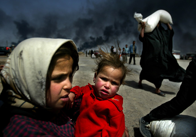 An Iraqi girl holds her sister as she waits for her mother (R) to bring over food bought in Basra, March 29, 2003. (Reuters/Jerry Lampen)