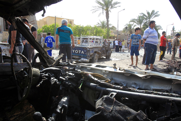 A picture taken from the inside of a damaged car shows Iraqis gathering at the site of car bomb explosion near a Shiite islamic center in the Baghdad neighbourhoods of Qahira on March 29, 2013 (AFP Photo / Ali Al-Saadi)
