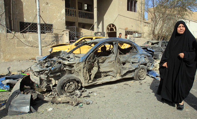 An Iraqi woman walks past a damaged car after a car bomb explosion near a Shiite islamic center in the Baghdad neighbourhoods of Qahira on March 29, 2013 (AFP Photo / Ali Al-Saadi)