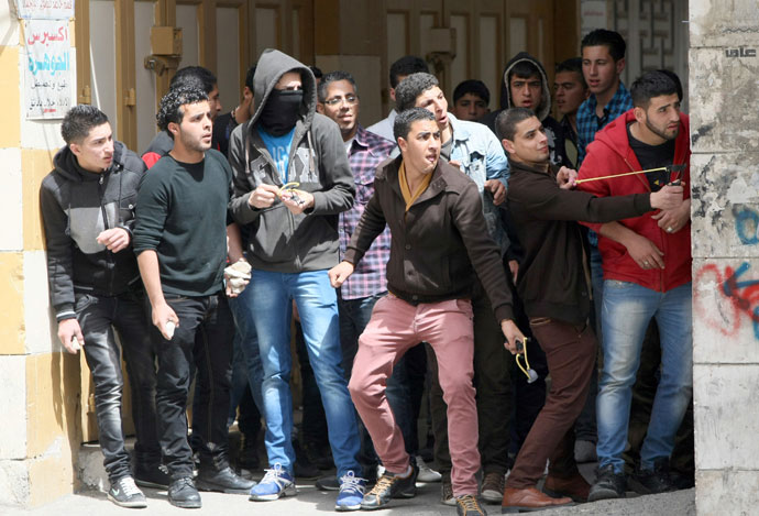 Palestinian stone throws take cover during clashes with Israeli security in the West Bank city of Hebron following the death of a Palestinian prisoner on April 2, 2013.(AFP Photo / Hazem Bader)