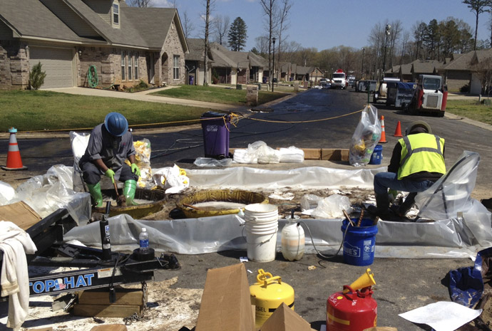 Workers scrub crude oil from their boots in the Northwoods subdivision where an ExxonMobil pipeline ruptured in Mayflower, Arkansas, April 1, 2013. (Reuters)